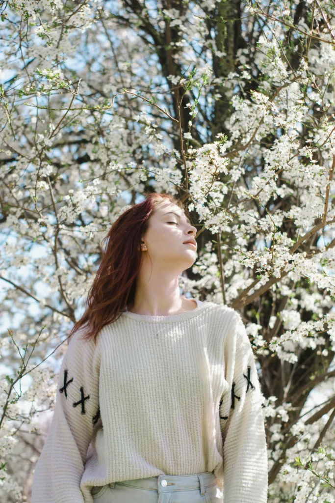 Femme qui retrouve le plaisir de respirer en plein air sous un arbre en fleurs.